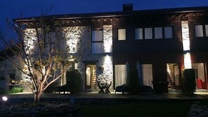 A two-story house with a stone facade, a patio with outdoor furniture, and a well-lit entrance. - Rural apartment El Hospital de Villahormes for 4 people (Llanes)