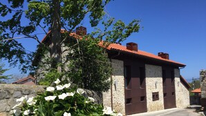 A stone building with a red-tiled roof, a stone wall, and a large tree in the foreground. - Rural apartment El Hospital de Villahormes for 4 people (Llanes)