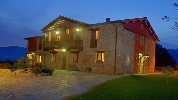 Un bâtiment en pierre doté d’un balcon, d’une entrée en pierre et d’une pelouse bien entretenue.