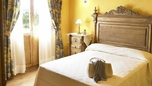 Une chambre avec un lit, une table de chevet, une lampe et une fenêtre avec des rideaux.