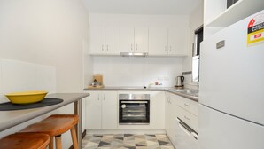 A compact kitchen with white cabinets, a built-in oven, and a refrigerator. - SELF CONTAINED-2 Bdrm Apartments (Albany)