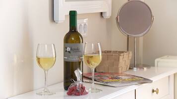A bottle of wine, two glasses, and a small bag of snacks on a white table.