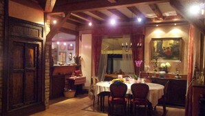 Un coin repas avec un plafond en bois, une table dressée pour quatre personnes et un lustre.