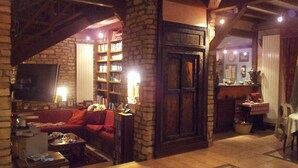 Un salon chaleureux avec une cheminée, une bibliothèque, un canapé et un téléviseur.