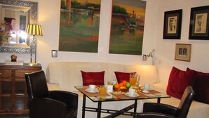 Un comedor con una mesa para dos, sillas, un sofá y obras de arte en las paredes.