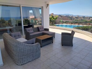 A balcony with wicker furniture, a pool, and a view of the landscape.