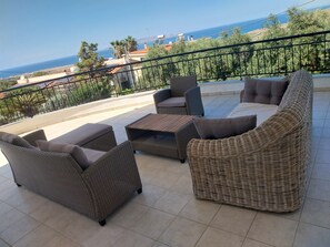 A balcony with wicker furniture, a view of the sea, and a railing.