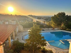 Une piscine dotée d’une terrasse en pierre et offrant une vue sur le paysage urbain en arrière-plan.