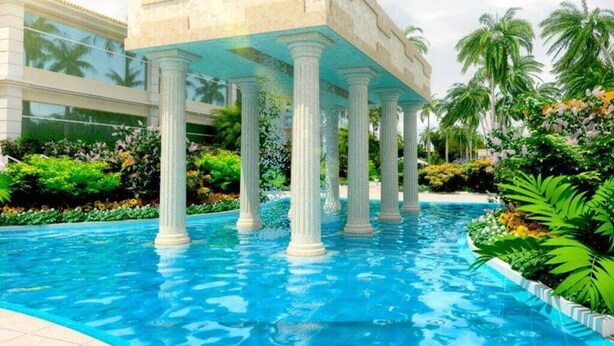 Ein Schwimmbecken mit weißen Säulen und einem Gebäude im Hintergrund.