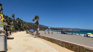 A beach with a stone wall, palm trees, and beach chairs. - Marbella Villa on the beach (Marbella)
