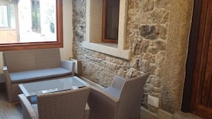 A cozy corner with a stone wall, a cushioned bench, and a glass-top table.