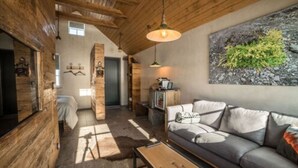 A rustic wooden interior with a sofa, a coffee table, and a painting of greenery. - Torfhús Retreat (Bláskógabyggd)