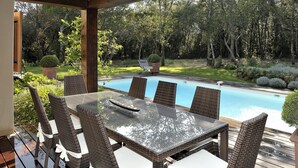 An outdoor dining area with wicker furniture and a view of a swimming pool. - House A Sùvara ***** private pool, park with trees 15 hectares, 5 min PORTICCIO (Cauro)