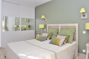 A bedroom with a large bed, a wardrobe, and two bedside lamps.