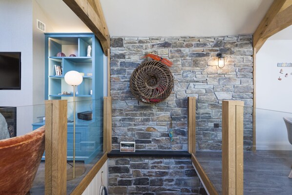 A stone wall with a woven basket decoration, a blue shelving unit, and a wooden floor. - Wella 5* Gold Rated Luxury Cottage (St Ives)