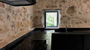 A kitchen with stone walls, a window, and a sink.