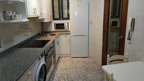 A compact kitchen with a washing machine, microwave, and refrigerator. - Apartment for groups in Logroño (Logroño)