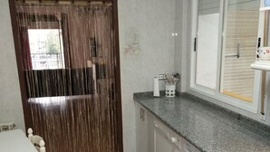 A compact kitchen with a washing machine, a countertop, and a dining area with a table and chairs. - Apartment for groups in Logroño (Logroño)
