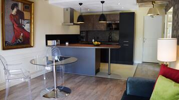 Une cuisine moderne dotée d’un îlot central, de luminaires suspendus et d’un coin repas avec une table et des chaises en verre.