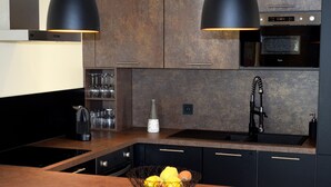 Eine moderne Küche mit dunklen Schränken, einer schwarzen Arbeitsplatte, einem eingebauten Backofen und einem Spülbecken mit Armatur.