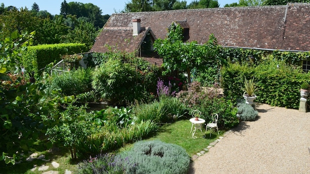 Ein rustikales Haus mit Garten, einem Kiesweg und einem kleinen weißen Tisch.