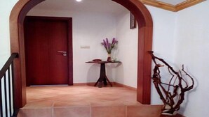 A staircase leading to a door, a small table with a vase of flowers, and a decorative branch on the wall.