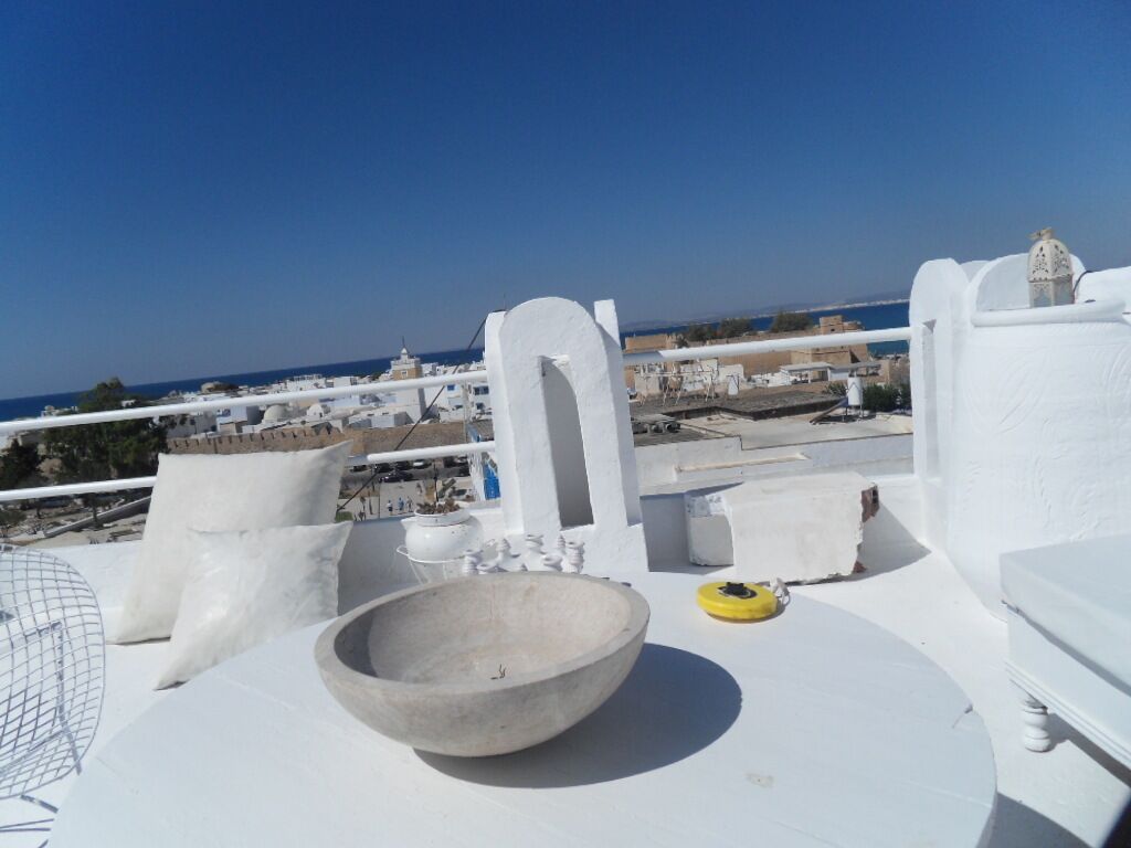 A white room with a large bowl, a yellow object, and a view of the sea and buildings.