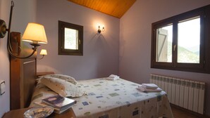 Una camera da letto con un letto, un comodino con una lampada, una finestra e un termosifone.