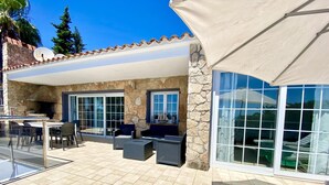 An outdoor patio with stone walls, a glass table, and outdoor furniture.