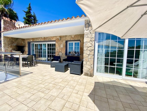 An outdoor patio with stone walls, a glass table, and outdoor furniture.