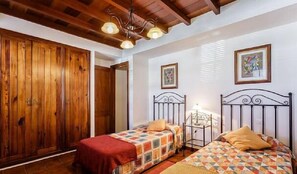 Un dormitorio con dos camas, un armario de madera y una lámpara en el techo.
