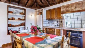Une cuisine rustique avec des meubles en bois, un dosseret carrelé et un coin repas avec une table mise pour deux personnes.