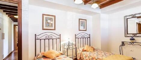 Een slaapkamer met twee bedden, houten balken in het plafond en een spiegel.