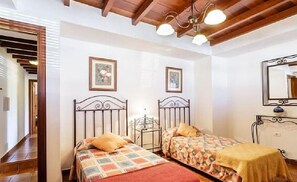 Camera da letto con due letti, travi in legno al soffitto e uno specchio.