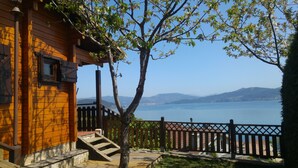 Ein Holzhaus mit einer Treppe, die zu einer Terrasse mit Blick auf einen See und Berge führt.