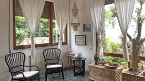 Een kamer met twee rieten stoelen, een klein rond tafeltje en een decor kast.