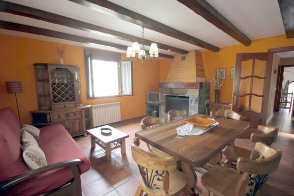 A dining area with a wooden table and chairs, a fireplace, and a red sofa. - Miguelo apartments for 6 people (Plan)