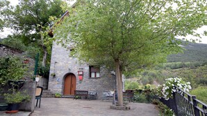 A stone building with a wooden door, outdoor seating, and a view of a hillside. - Miguelo apartments for 6 people (Plan)