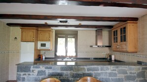 A kitchen with stone countertops, wooden cabinets, and a stone island with two chairs. - Miguelo apartments for 6 people (Plan)