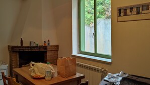 Een eethoek met een tafel, stoelen, een open haard, een raam en een grill.