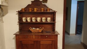 Een houten kast met verschillende planken, een mand en een deur met een greep.