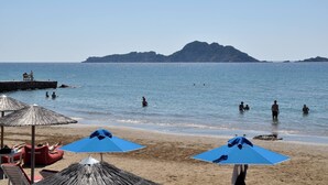 Una spiaggia con ombrelloni, lettini e persone che nuotano nell'acqua.