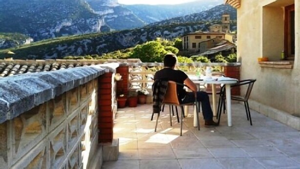 A man sitting at a table on a terrace with a view of mountains. - Casa Javier for 8 people (Rodellar)