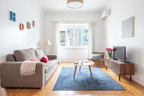 A living room with a sofa, a coffee table, a TV stand, and a window with curtains. - Casa da Avenida IV Lisboa (Lisbon)