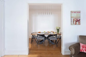 Un comedor con una mesa de madera, cuatro sillas y una lámpara colgante.