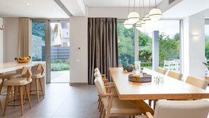 Een moderne eethoek met een lange houten tafel, stoelen en hanglampen.