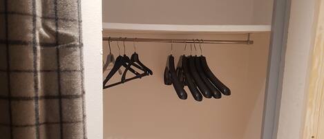 Un vestidor con estantes de madera y perchas negras.