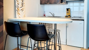 A modern kitchen with a white countertop, black chairs, a microwave, and a wooden cabinet. - Studio with mountain corner Exceptional location in the resort (AVORIAZ)