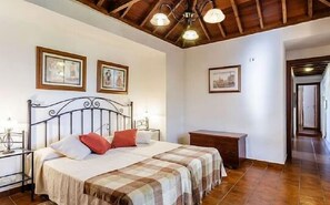 A bedroom with a bed, two bedside tables, a wooden bench, and framed pictures on the wall.