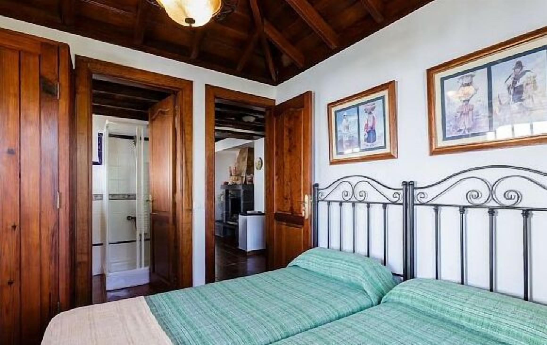 Une chambre à coucher avec un lit, des portes en bois et des tableaux encadrés accrochés au mur.